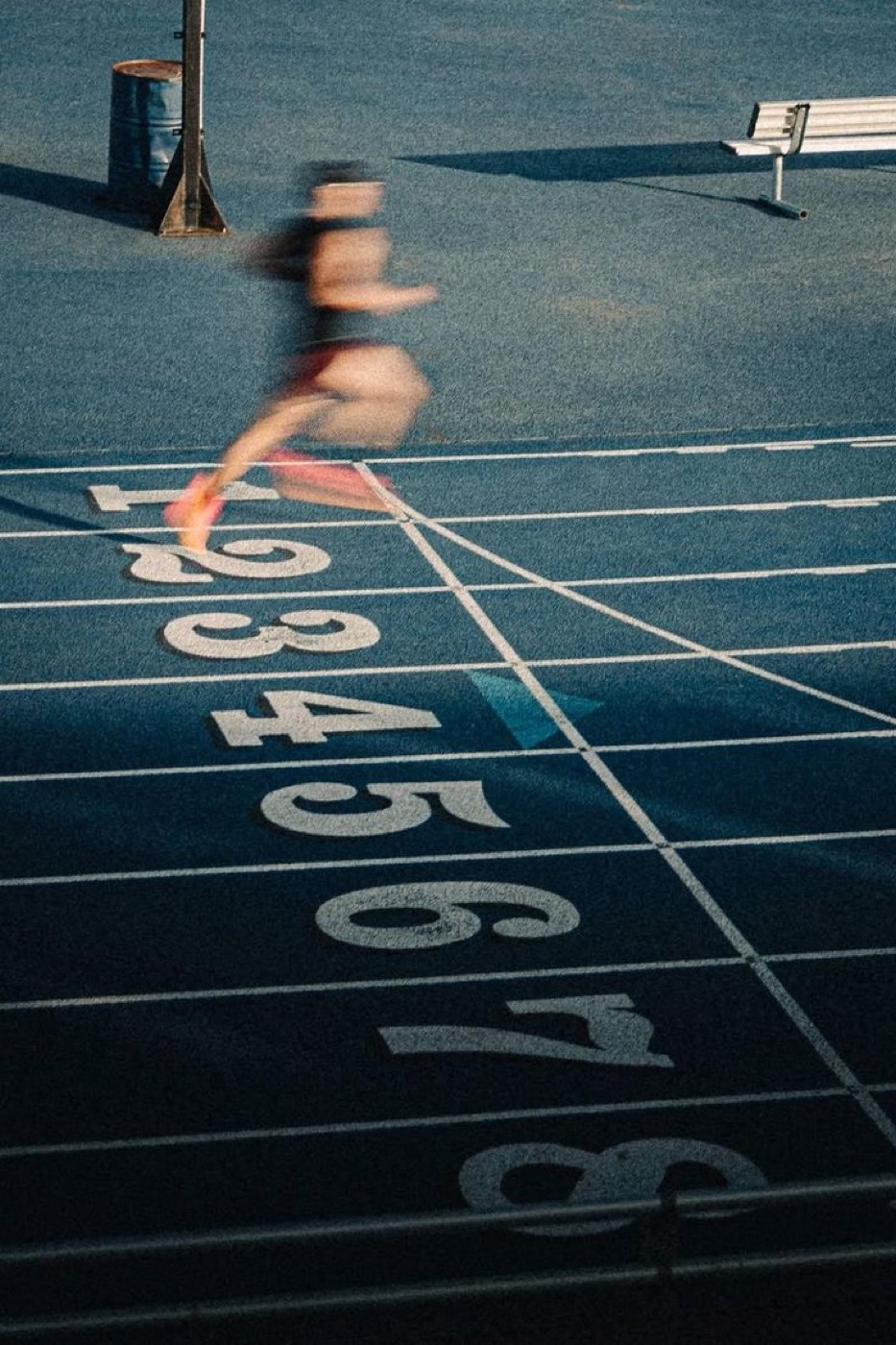 A runner crossing a track finish line at speed
