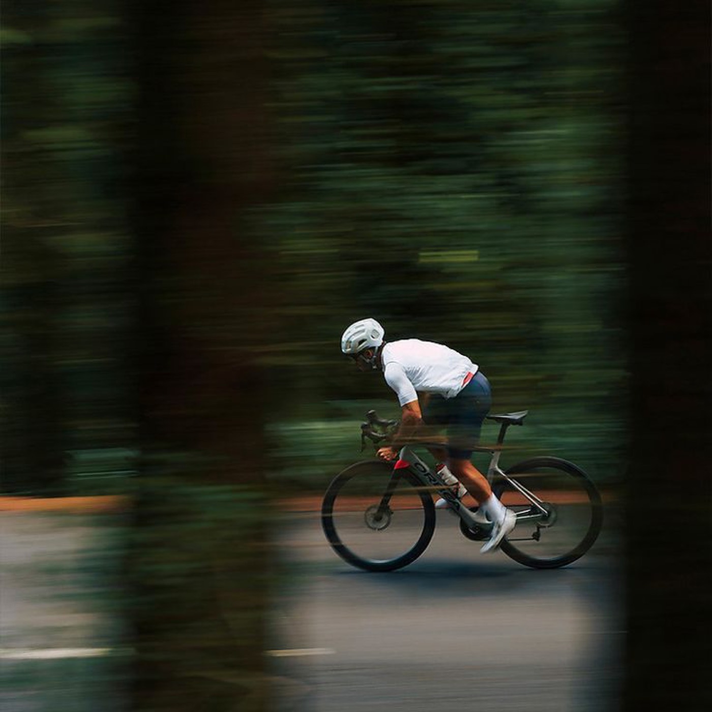 A cyclist riding a long forest road