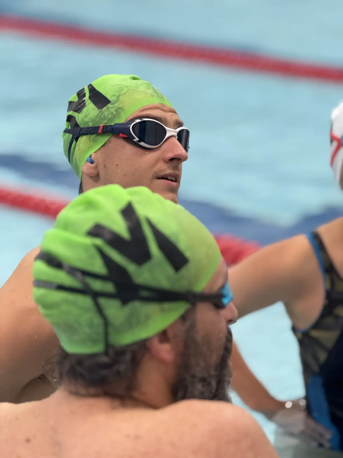 An Unbroken Triathlon Club swimmer in club cap at the pool